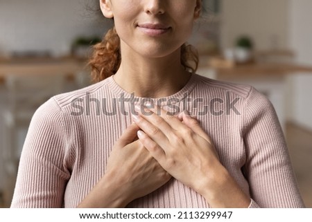 Close up cropped view young attractive Hispanic woman stand alone indoor put folded palms on chest feeling grateful and appreciation, express sincere feelings. Believe, charity, body language concept Royalty-Free Stock Photo #2113299947
