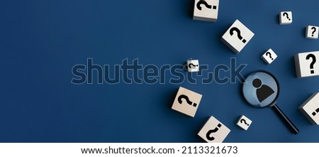 Concept of finding a creative idea or solving a problem. Question mark on wooden cubes and a magnifying glass with a human icon on a blue background