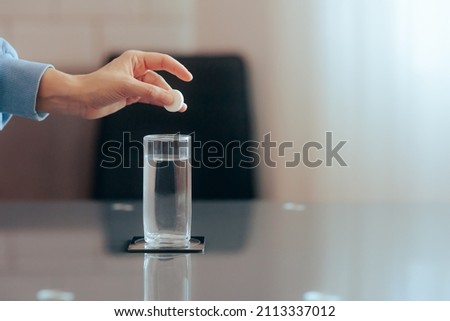 
Hand Dropping an Effervescent Pill of Calcium and Magnesium in Water. Medical beverage made from soluble fizzy vitamin tablet 
