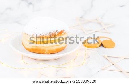 A donut with powdered sugar and cream in a saucer with coins and wooden stars of David.