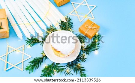 Donut, candles, star of David, spruce branches, garland and gifts on blue.