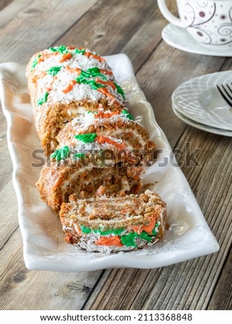 A carrot cake jelly roll on a platter, sliced into, ready for serving.