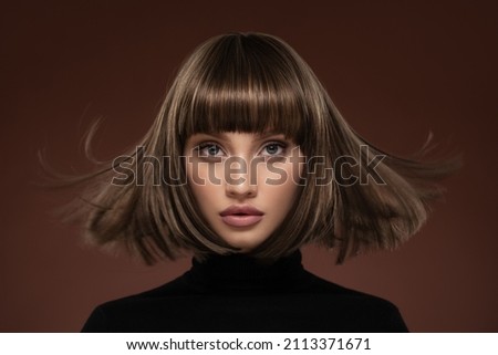 Portrait of a beautiful brown-haired woman with a short haircut on a brown background Royalty-Free Stock Photo #2113371671
