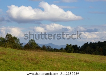 Beautiful photo of a green landscape with blue skies and clouds of Ashville North Carolina's Blue Ridge Mountains during a road from the road