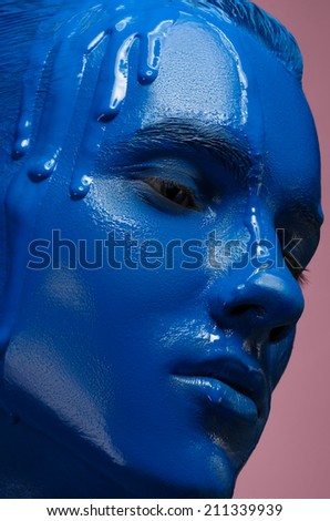 Portrait of a man poured blue paint on a pink background