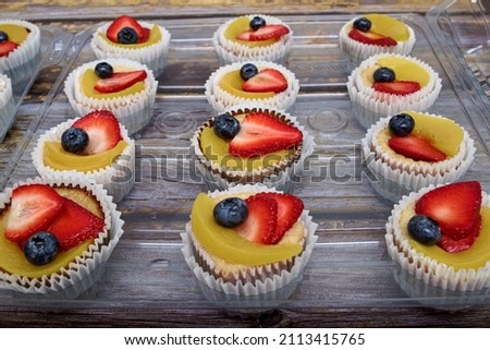 Small pies decorated with fruits on wooden table. Homemade dessert.