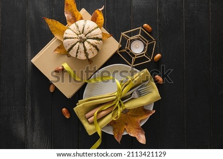 Composition with table setting and autumn decor on black wooden background