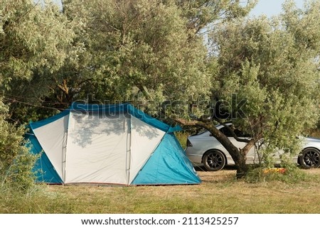 Traveling by car with a tourist tent on the background of green trees. Travel in comfort