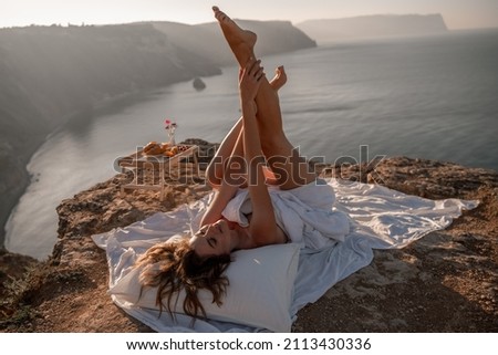 Woman wake up in bed wuth duvet and pillow over nature sea background outdoors. Back view. Good morning. Freedom concept.