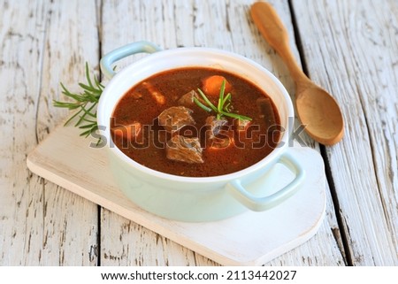 hearty homemade goulash soup on a wooden table Royalty-Free Stock Photo #2113442027