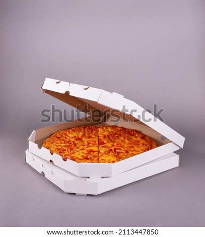 Two fragrant tasty pizzas in a box on a gray background Royalty-Free Stock Photo #2113447850