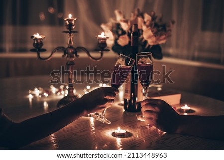 Hands man and woman holding glasses of wine having romantic candlelight dinner at table at home. Hands man and woman holding glass of wine. Concept of Valentine's day or Candlelight date at night. Royalty-Free Stock Photo #2113448963