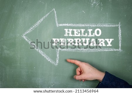 Hello February. Direction arrow on a green chalk board.