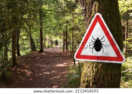 Infected ticks warning sign in a forest. Risk of tick-borne and lyme disease. Royalty-Free Stock Photo #2113458593
