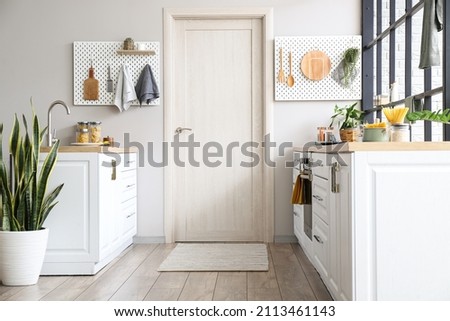 Interior of modern kitchen with white counters, door and peg boards Royalty-Free Stock Photo #2113461143
