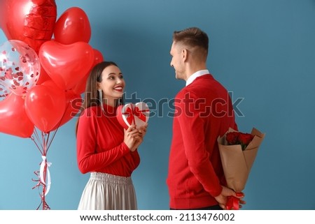 Young man greeting his girlfriend for Valentine's Day on color background Royalty-Free Stock Photo #2113476002
