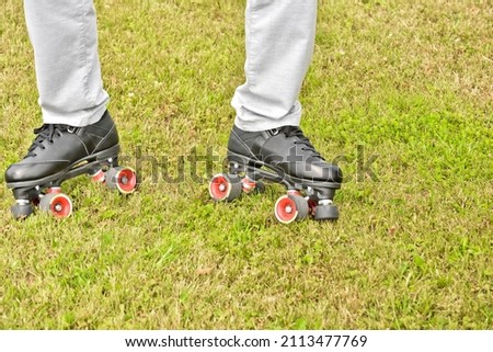 Men's legs in roller skates on the background of the lawn. Roller skating during summer leisure, recreation and entertainment.
