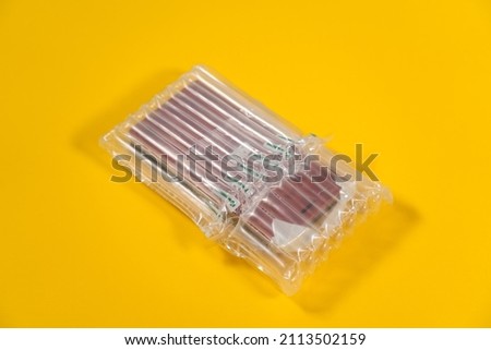 Close-up view stock photography of object packed in bubble plastic protective from cracks wrap laying isolated on bright yellow background