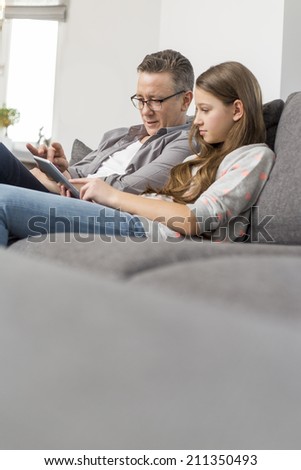 Father and daughter using digital tablet together at home