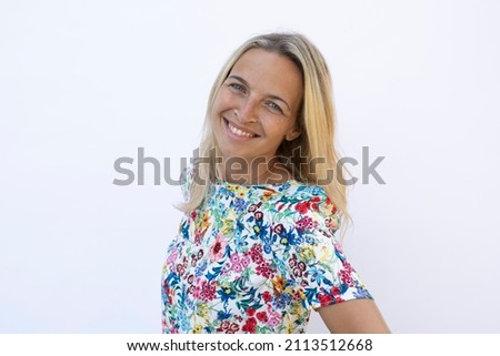 beautiful young woman with blond hair and flower shirt posing in front of white background
