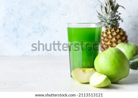 Glass of healthy green juice and fresh apples on white background