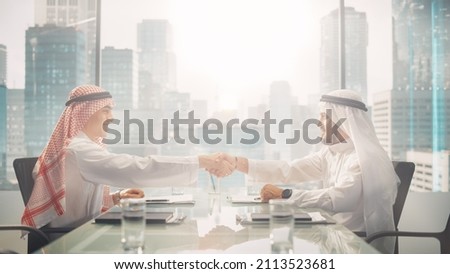 Two Successful Emirati Businessmen in White Traditional Kandura Sitting in Office and Signing Contract. Business Partners Shake Hands on Lucrative Investment. Saudi, Emirati, Arab Businessman Concept.