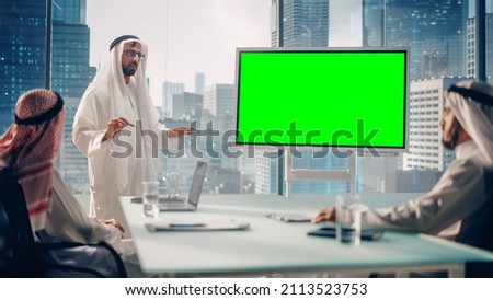 Emirati Businessman Holds Meeting Presentation for Business Partners. Arab Manager Uses Digital Whiteboard with Horizontal Green Screen Mock Up Display. Saudi, Emirati, Arab Office Concept.