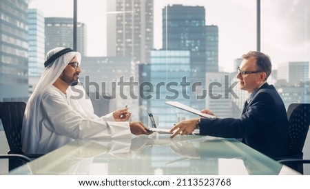 Two Businessmen with Different Nationalities Sitting in Office and Signing Contract. Arab Business Partner Make with Investor Financial Deal. Saudi, Emirati, Arab Businessman Concept.