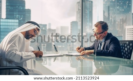 Two Businessmen with Different Nationalities Sitting in Office and Signing Contract. Arab Business Partner Make with Investor Financial Deal. Saudi, Emirati, Arab Businessman Concept.