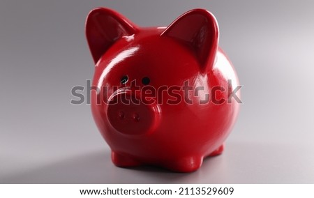 Closeup of red piggy banks for coins on gray background
