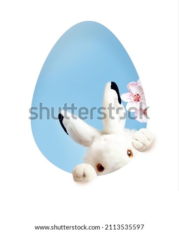 Easter card with paper cut egg shape frame with bunny. Copy space for text. Easter rabbit with flower. Happy Easter on blue background
