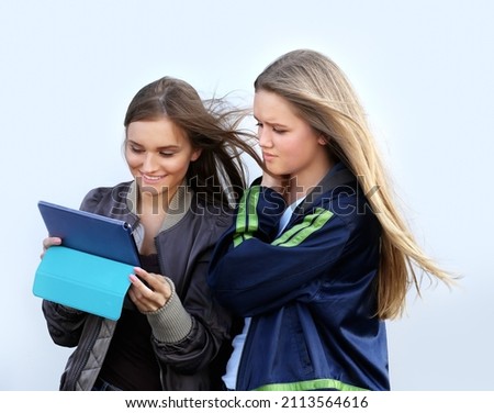 two girls walking the streets, laughing ,taking pictures ,using smartphone