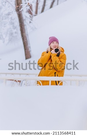 Positive girl photographer takes pictures of winter in a snowy park