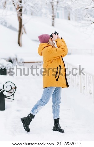 Positive girl photographer takes pictures of winter in a snowy park