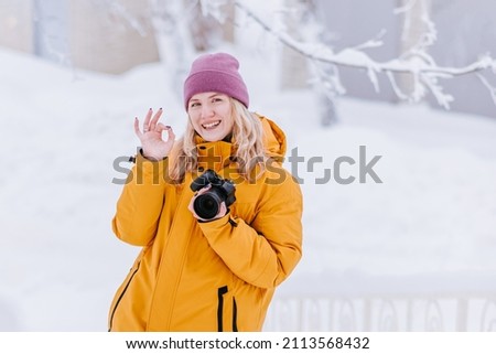 Smiling girl photographer takes pictures of winter in snowy park