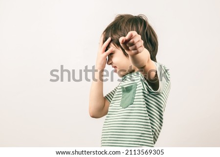 White 6 years old boy was hit in the face, covering his head threatens the enemy with a fist. Kid quarreling and fighting. Child abuse concept