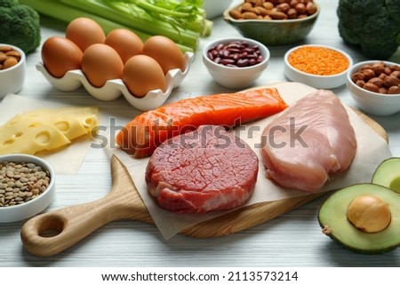 Fresh meat and other products on white wooden table. Sources of essential amino acids