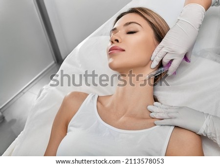 Smoothing female neck skin with injections in neck at cosmetic clinic. Neck skin rejuvenation and contouring, mesotherapy and biorevitalization Royalty-Free Stock Photo #2113578053