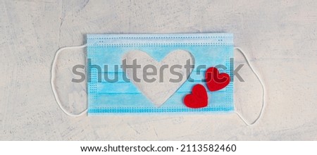 banner with Medical mask with cut-out silhouette of heart and two red hearts on white stone background. Valentine's Day background. Valentine's Day concept. Flat lay. Top view. Copy space