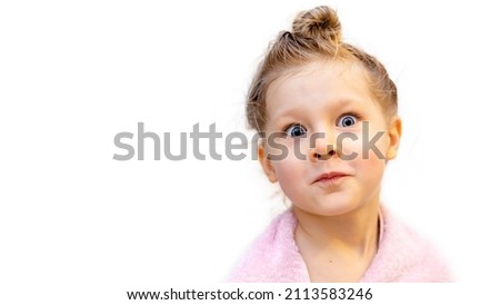 a 5-year-old girl in a pink towel on a white background makes funny faces with wet hair twisted into a bun, the child washed and left the bathroom