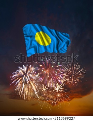 Holiday fireworks in evening sky and flag of Palau for National Independence day