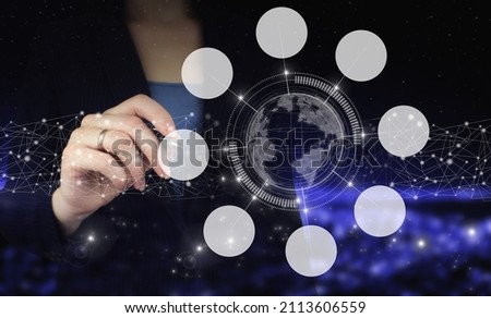 Hand holding digital graphic pen and drawing digital hologram planet, circular diagram sign on city dark blurred background. Innovation, big data concept technology