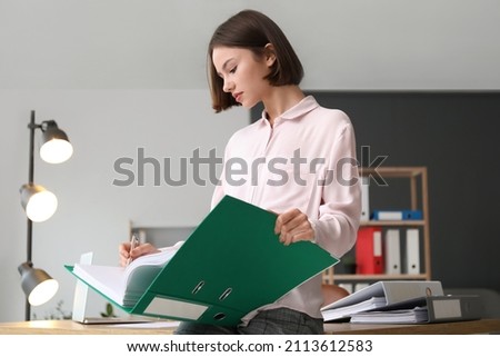 Young woman working with documents in office Royalty-Free Stock Photo #2113612583