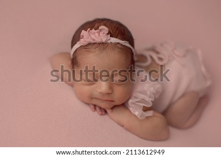 Closeup of smiling newborn baby girl lying on pink cloth. Newborn photography