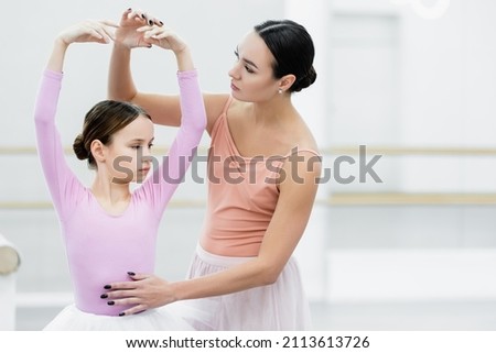 preteen girl practicing choreographic elements near young ballet master Royalty-Free Stock Photo #2113613726