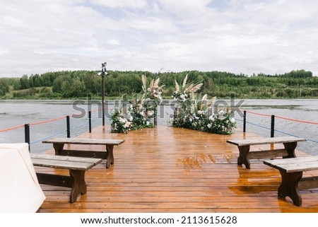 Blue sky and river, fresh flowers and compositions. Organization of the wedding ceremony on the pier. Wedding arch decorated with flowers. Wedding atmosphere, decorations, celebration.