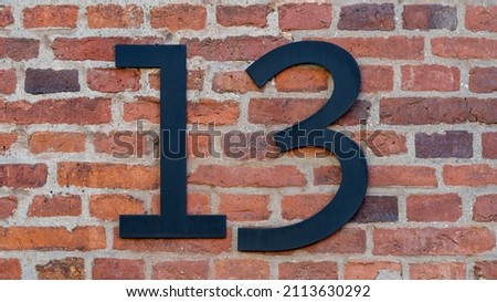 House number thirteen (13) on a red brick wall. High resolution photo.
