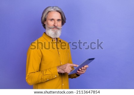 Portrait of attractive skilled gray-haired man using tablet app 5g search web isolated over vibrant violet purple color background
