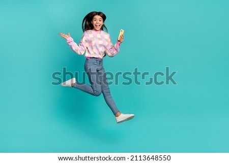 Full length body size view of beautiful trendy cheery girl jumping using cell having fun isolated over bright teal turquoise color background