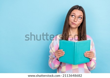 Photo of smart curious lady read book look empty space ponder question wear specs sweater isolated blue color background